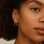 Close-up of a woman wearing a gold hoop earring with a neutral background